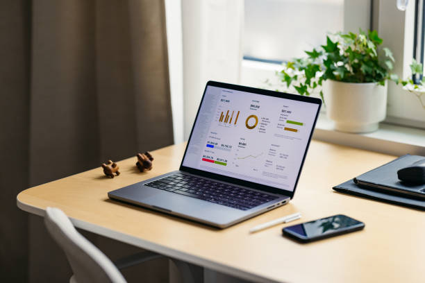 A wide angle view of a laptop (charts on the screen) and a smartphone on the table.